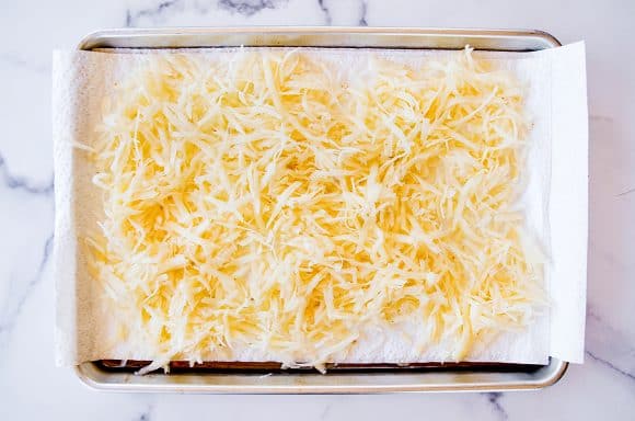 Shredded potatoes on top of paper towel-lined baking sheet