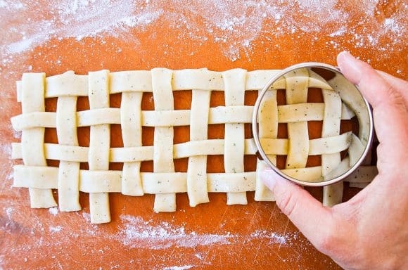 Hand holding circle cookie cutter over lattice 