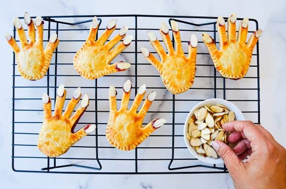 Hand pies with almond nails on top of cooling rack