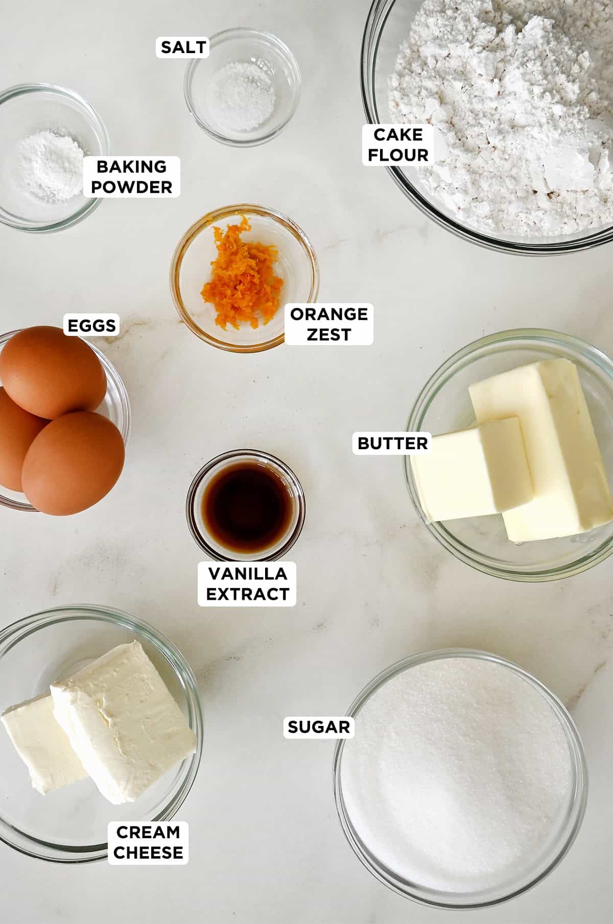 Ingredients to make cream cheese pound cake in various sizes of glass bowls.