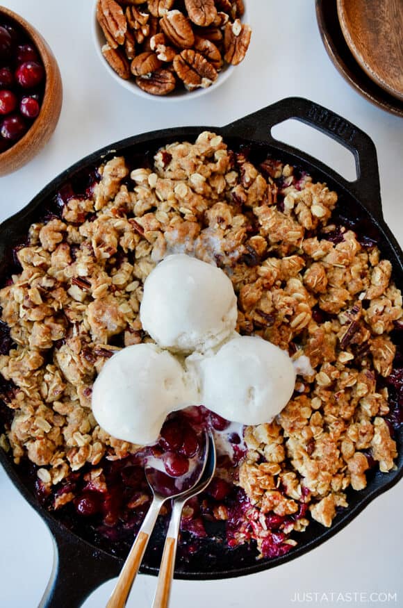A cranberry crisp with ice cream on top and spoons sticking out