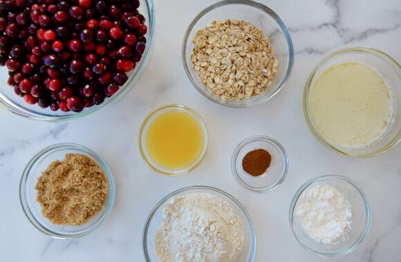 Ingredients in glass bowls including cranberries, oats and flour