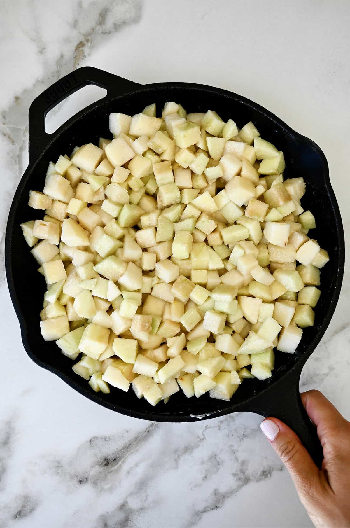 A skillet containing pear apple crisp filling.