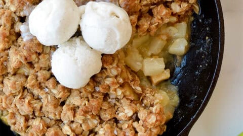 Apple pear crisp topped with three scoops of vanilla ice cream.