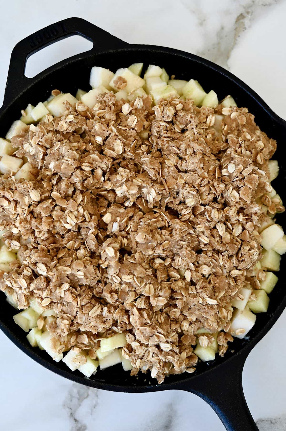 Unbaked apple pear crisp in a cast iron skillet.