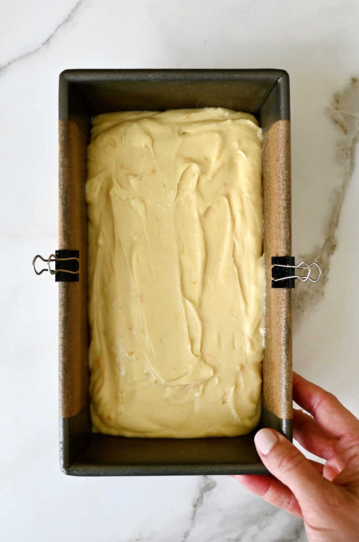 Cream cheese pound cake batter in a loaf pan lined with parchment paper.