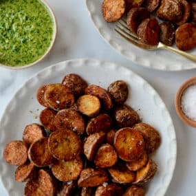 A top-down view of white plates containing roasted potatoes