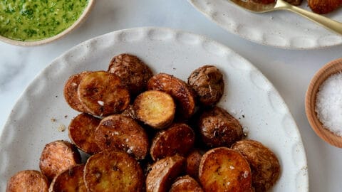 A top-down view of white plates containing roasted potatoes
