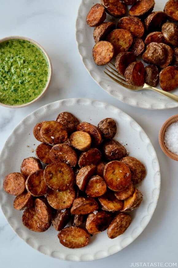 A top-down view of white plates containing roasted potatoes