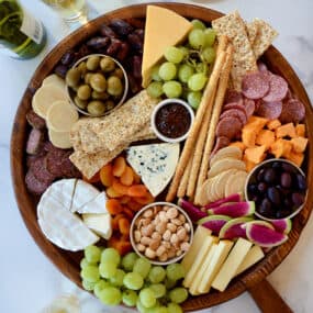 A top down view of a charcuterie board filled with meat, cheese, fruit and crackers