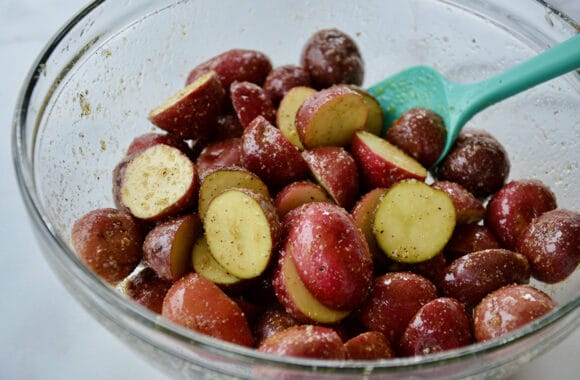 A glass bowl with potatoes and seasonings