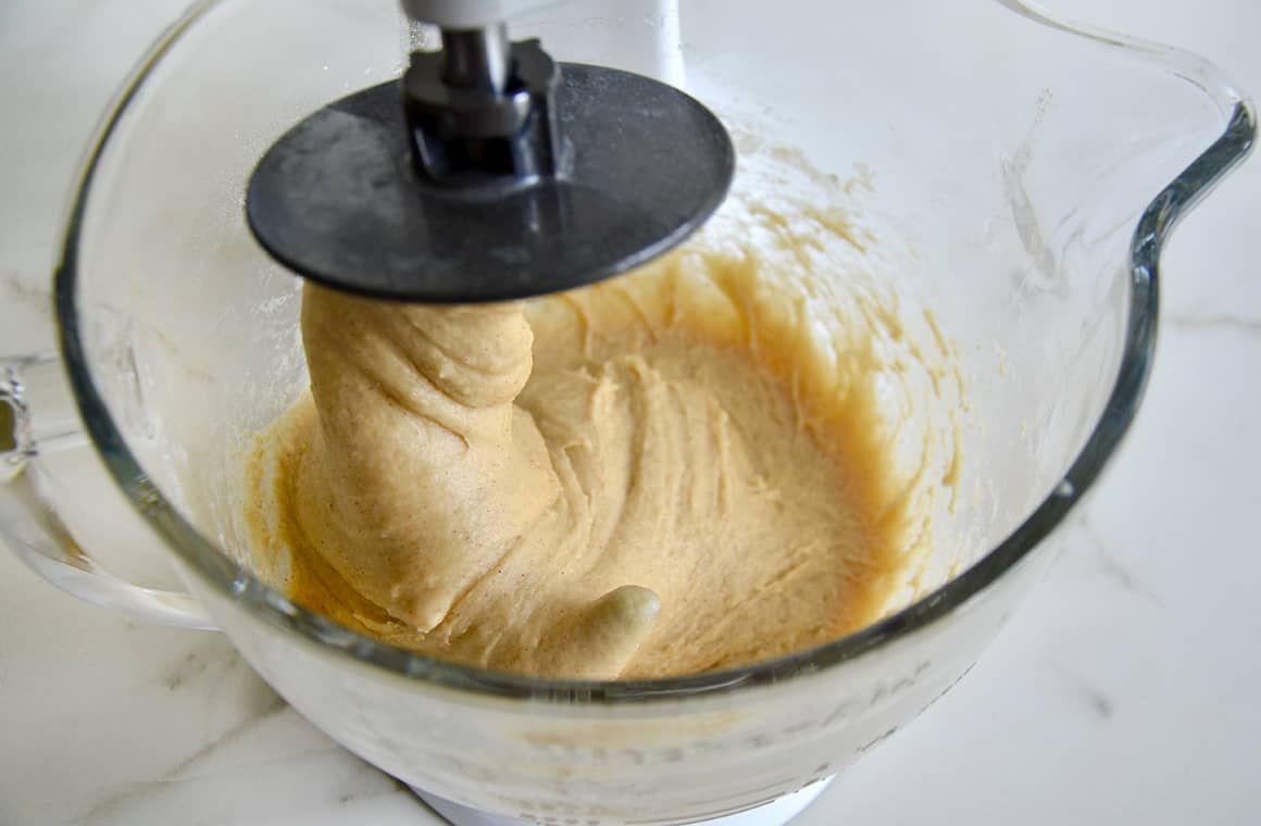 Yeasted dough in a glass stand mixer bowl with the dough hook attachment