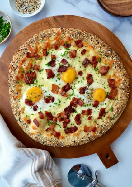 A top-down view of a bagel pizza with an everything seasoning crust