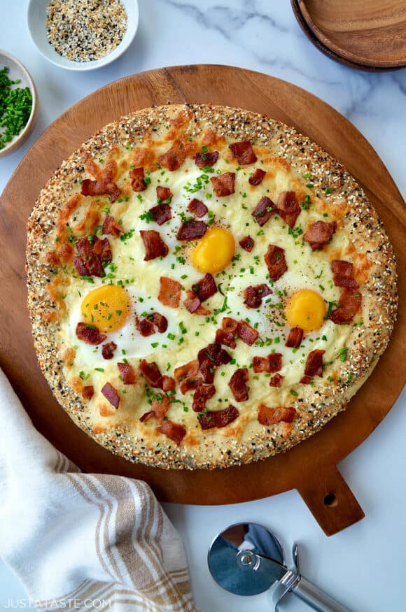 A top-down view of a bagel pizza with an everything seasoning crust