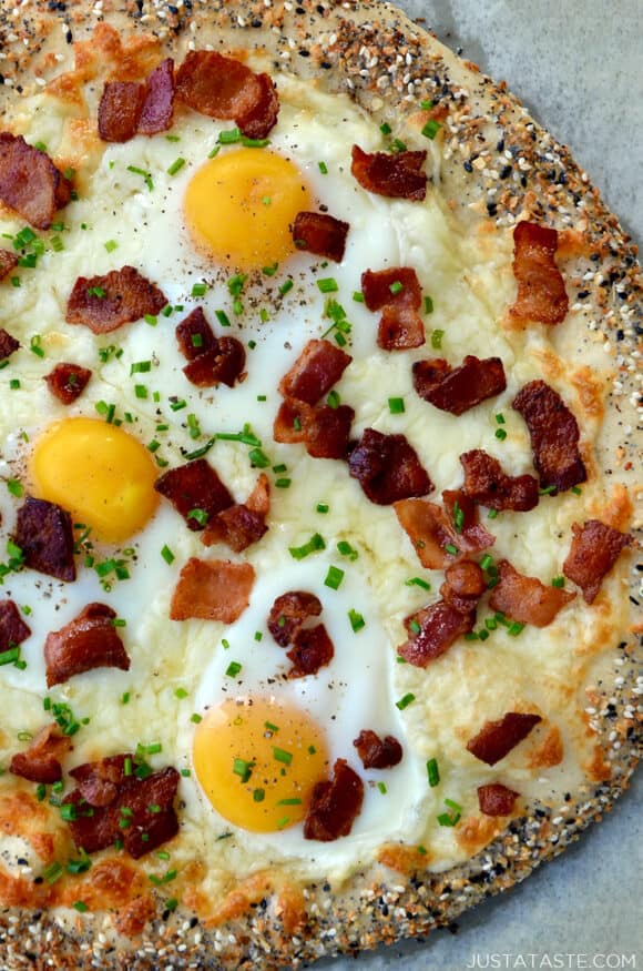 Closeup view of bagel breakfast pizza topped with crispy bacon, eggs and chives