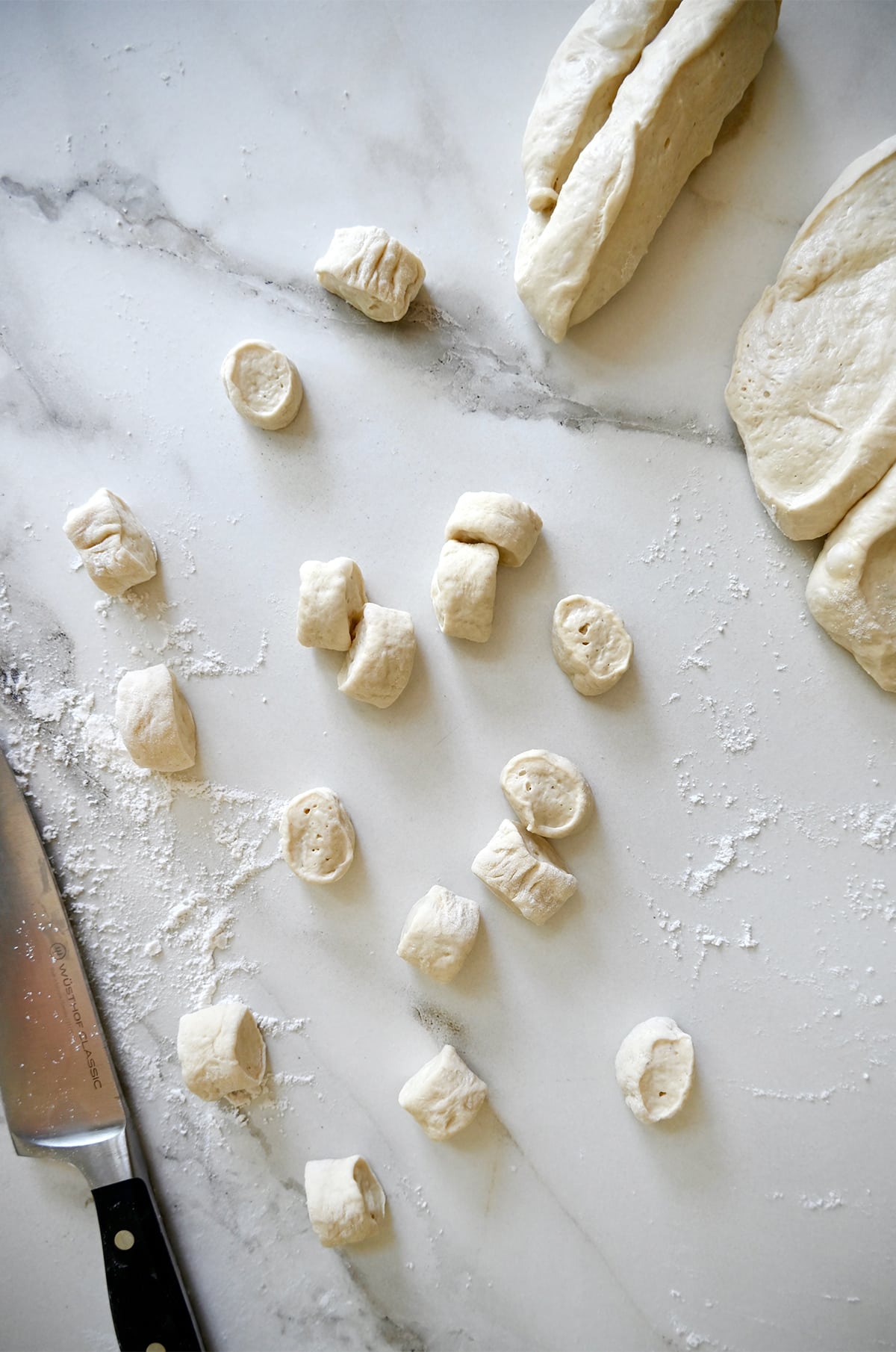 Pizza dough cut into small pieces on a floured surface.