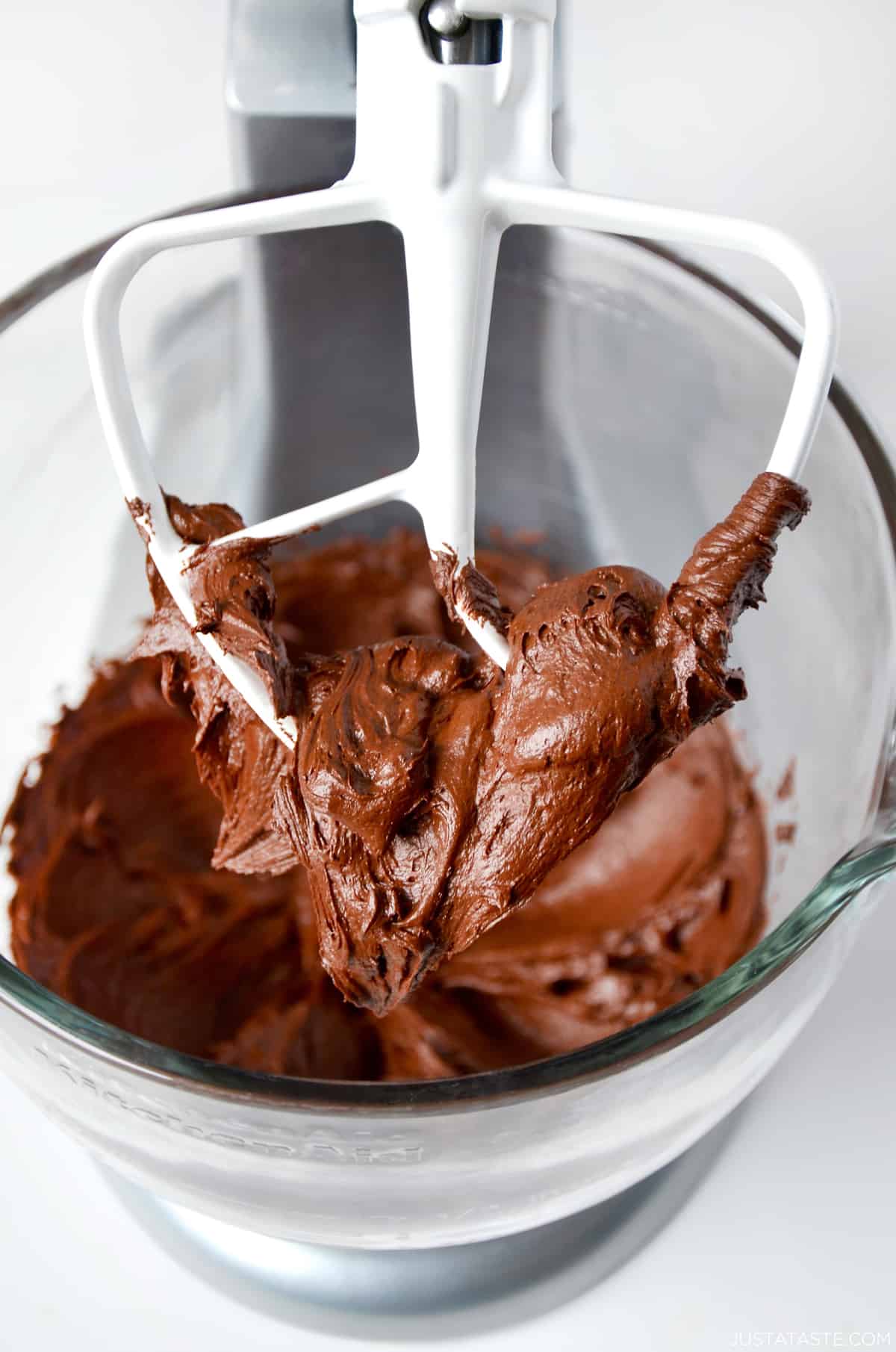 Chocolate buttercream frosting on the paddle attachment of a stand mixer.