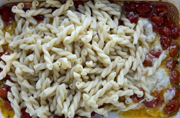 A top-down view of pasta, melted Brie cheese and roasted tomatoes