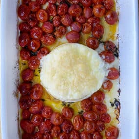 A top-down view of baked brie and roasted tomatoes in a baking dish