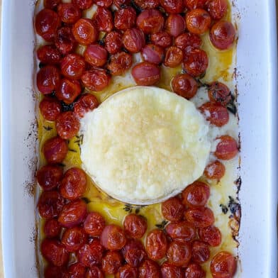 A top-down view of baked brie and roasted tomatoes in a baking dish