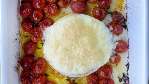 A top-down view of baked brie and roasted tomatoes in a baking dish