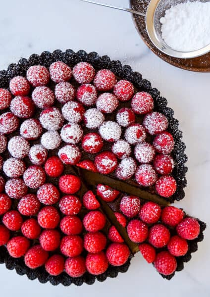 Top-down view of Easy No-Bake Chocolate Tart with Raspberries half dusted with powdered sugar