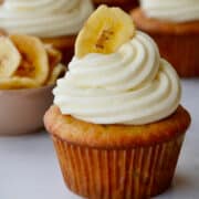 Banana Cupcake topped with piped cream cheese frosting and a dried banana chip