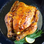 Simple Roast Chicken with Garlic and Lemon in a cast iron skillet with fresh rosemary