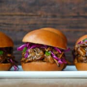 Slow Cooker Balsamic Honey Pulled Pork on a slider bun with purple cabbage and sliced scallions