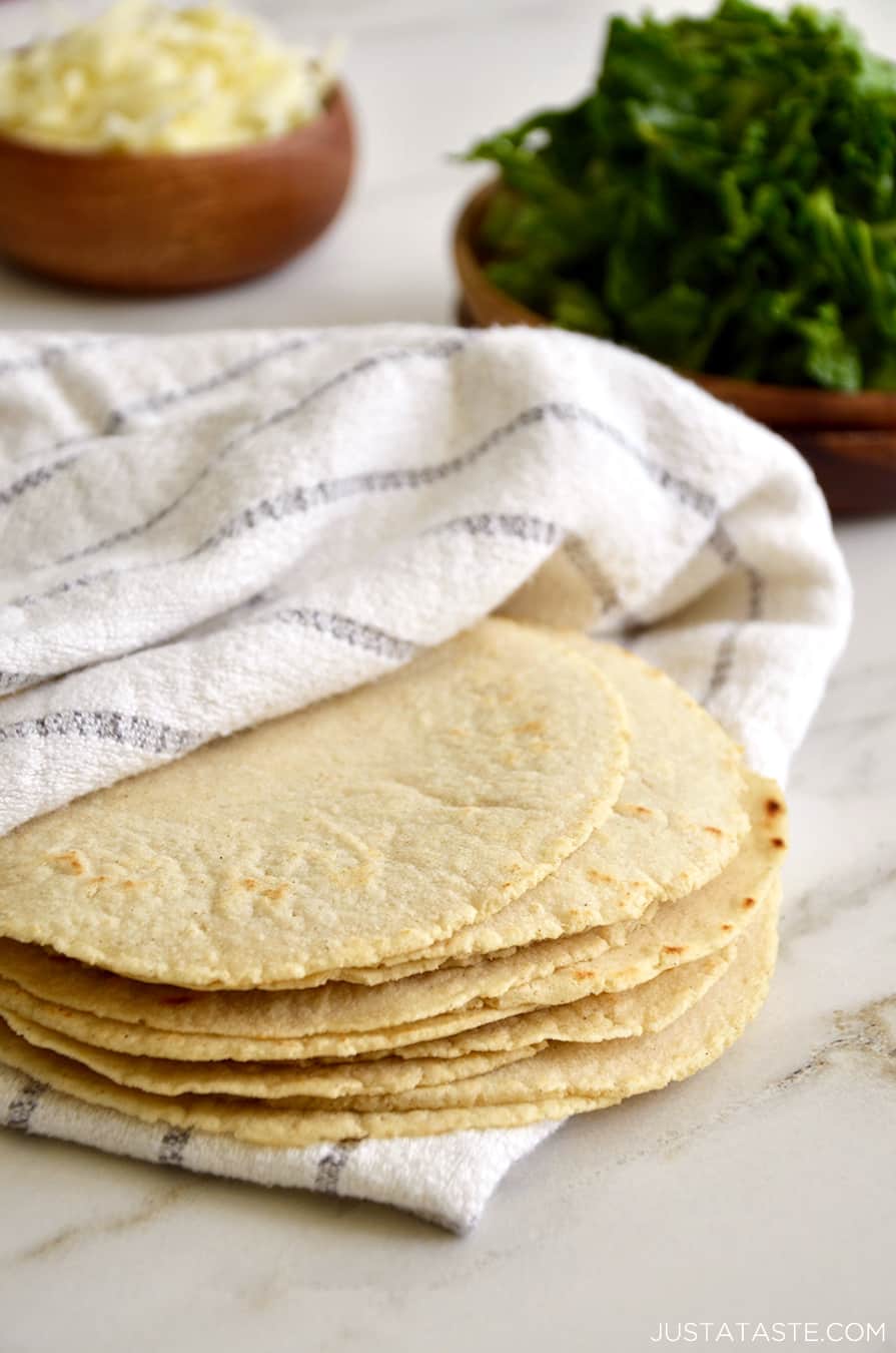 A stack of homemade corn tortillas inside a towel