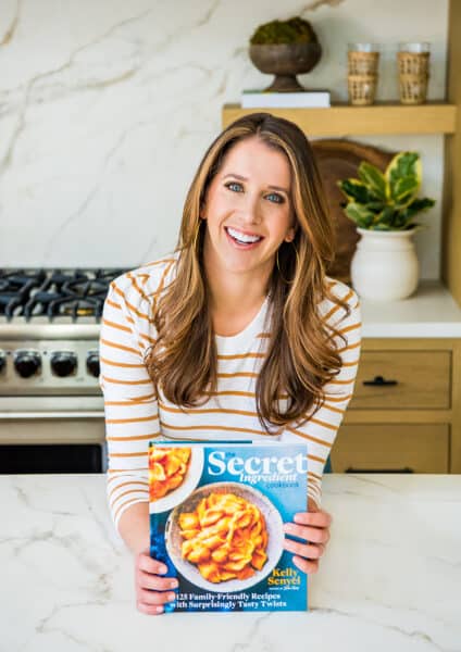 Kelly Senyei holding a copy of The Secret Ingredient Cookbook