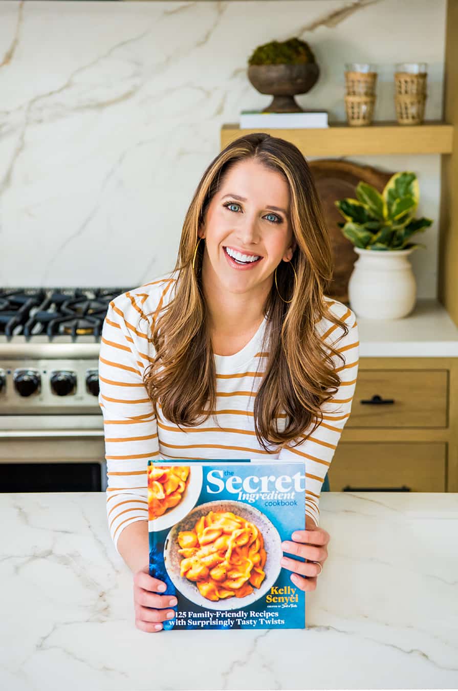 Kelly Senyei holding a copy of The Secret Ingredient Cookbook