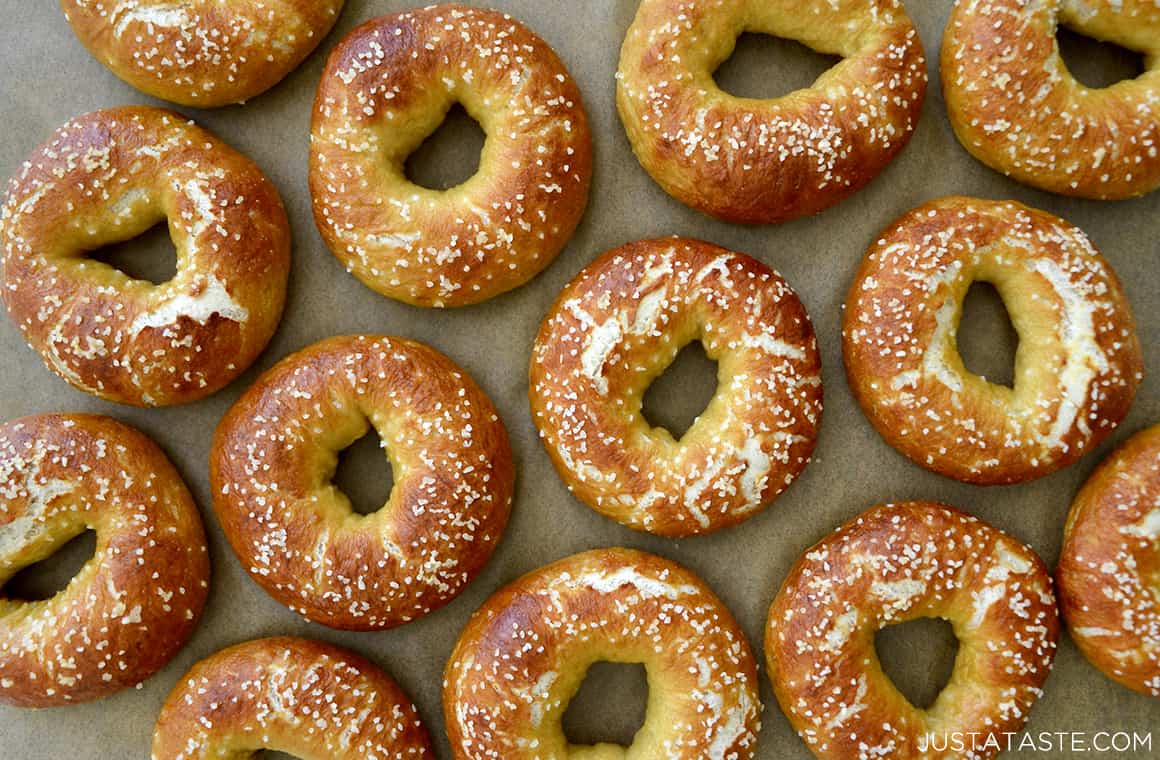 A top-down view of baked soft pretzel bagels on tan parchment paper