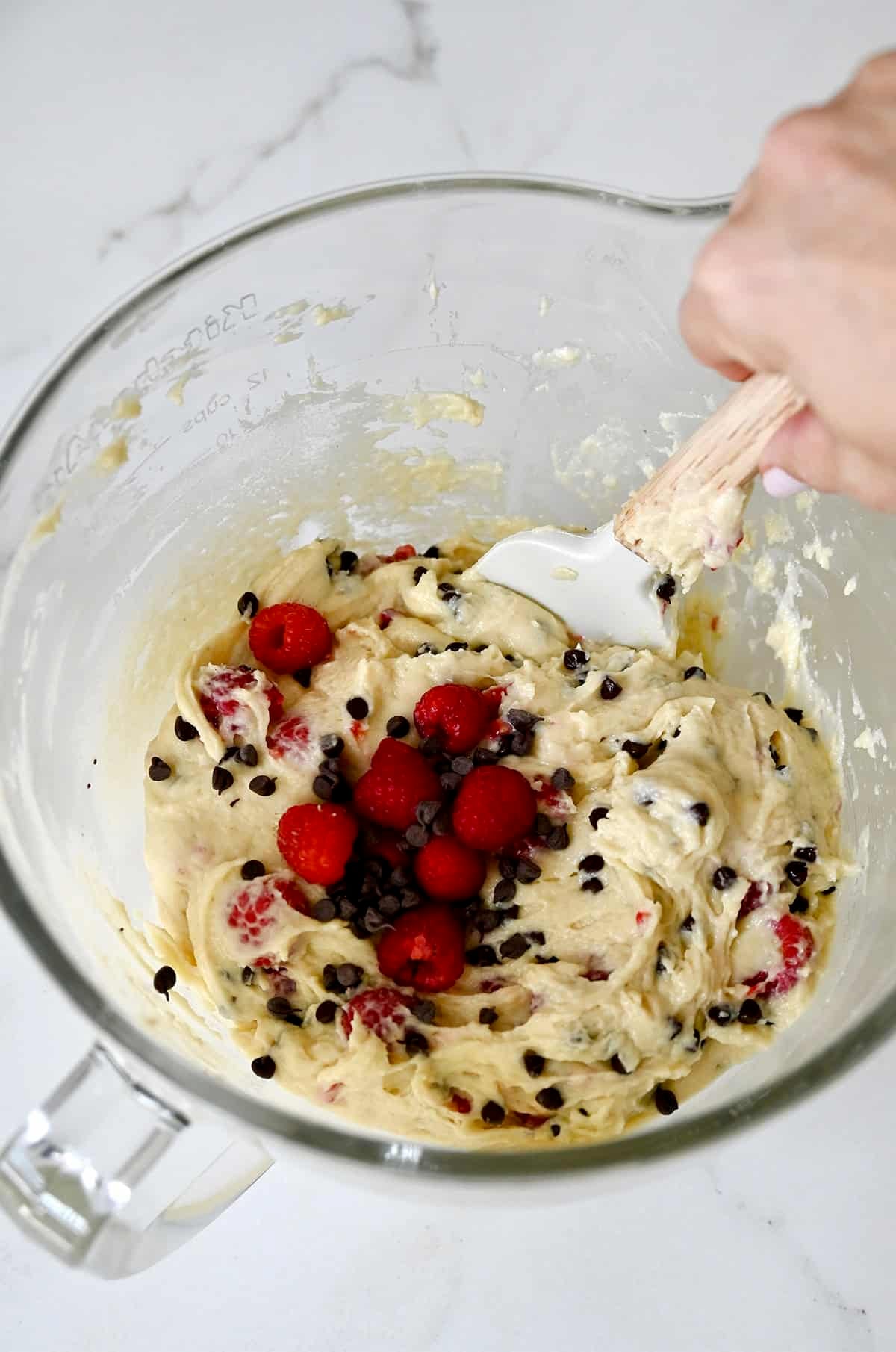 Folding fresh raspberries and chocolate chips into sour cream muffin batter.