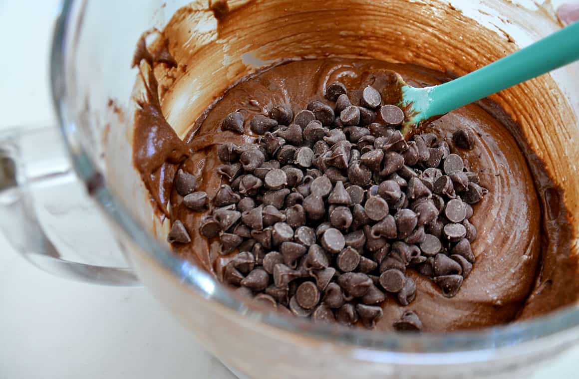 A glass bowl containing brownie batter with chocolate chips