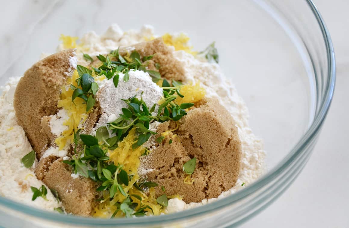 A glass bowl containing brown sugar, flour, thyme and lemon zest