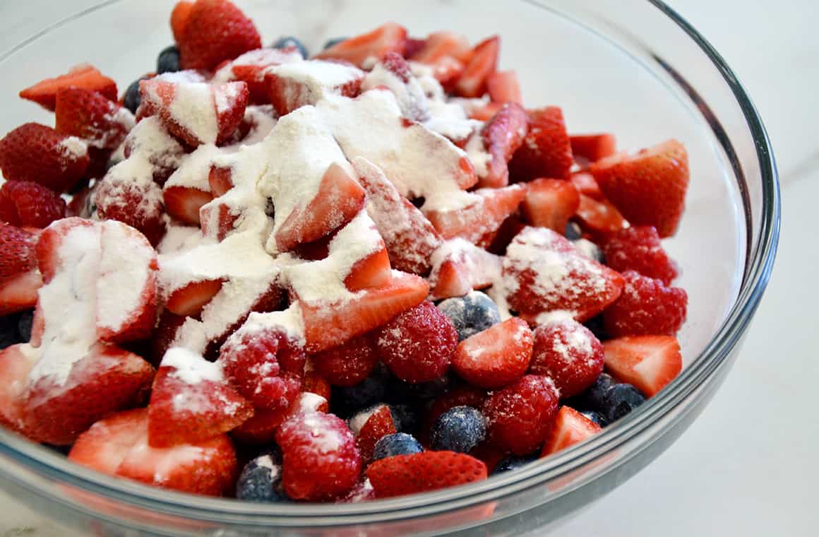 Strawberries, raspberries and blueberries in a glass bowl with flour