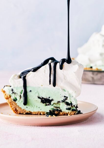Mint chocolate chip ice cream pie with a waffle cone crust topped with a thick layer of whipped cream and drizzled with chocolate syrup.