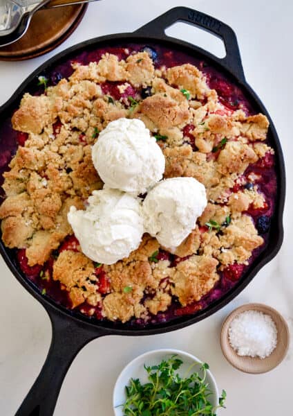 A cast-iron skillet with fruit crumble topped with ice cream