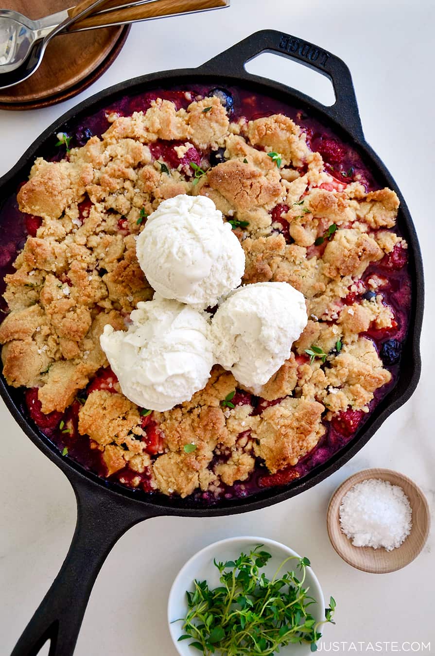 A cast-iron skillet with fruit crumble topped with ice cream
