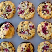 Top-down view of Raspberry Chocolate Chip Muffins in a muffin pan with text underneath that reads, "Raspberry Chocolate Chip Muffins" and the purple Just a Taste logo.