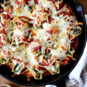 Stuffed shells with meat, cheese and spinach in a skillet with marinara sauce.