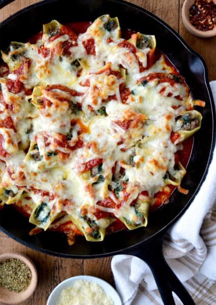 Stuffed shells with meat, cheese and spinach in a skillet with marinara sauce.