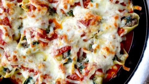 Stuffed shells with meat, cheese and spinach in a skillet with marinara sauce.
