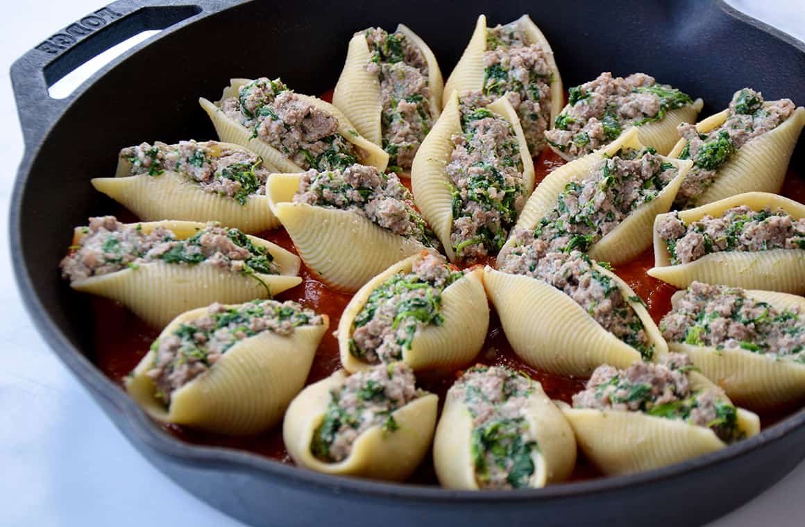 Jumbo shells arranged in a cast-iron skillet with marinara sauce