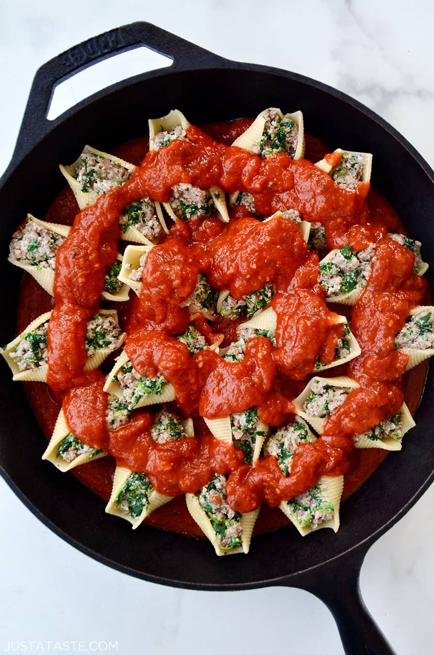 A cast-iron skillet with stuffed shells and tomato sauce on top