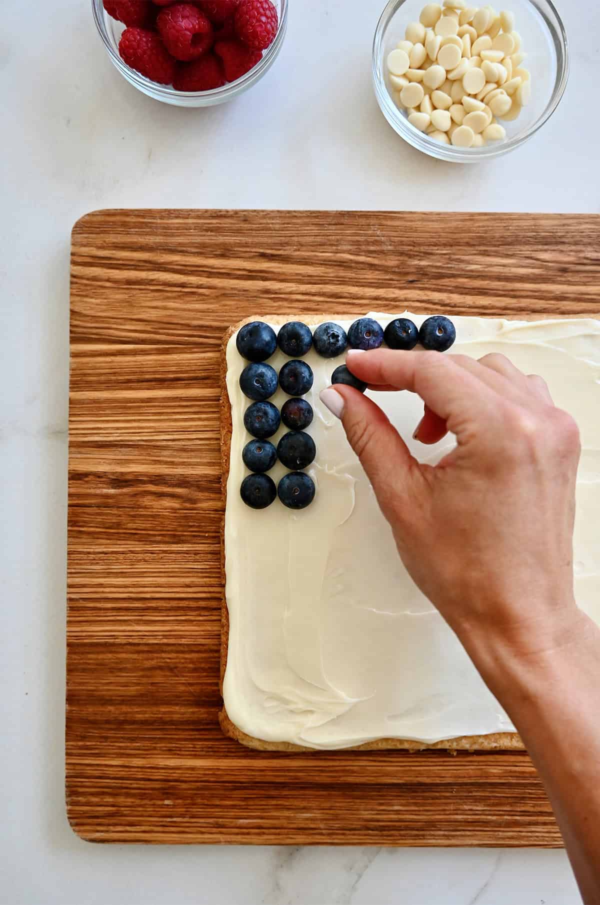 Adding berries to make a flag cake with cream cheese frosting.