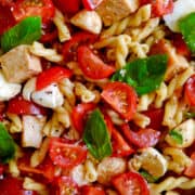 Close-up view of Bruschetta Pasta Salad with Chicken topped with fresh basil.