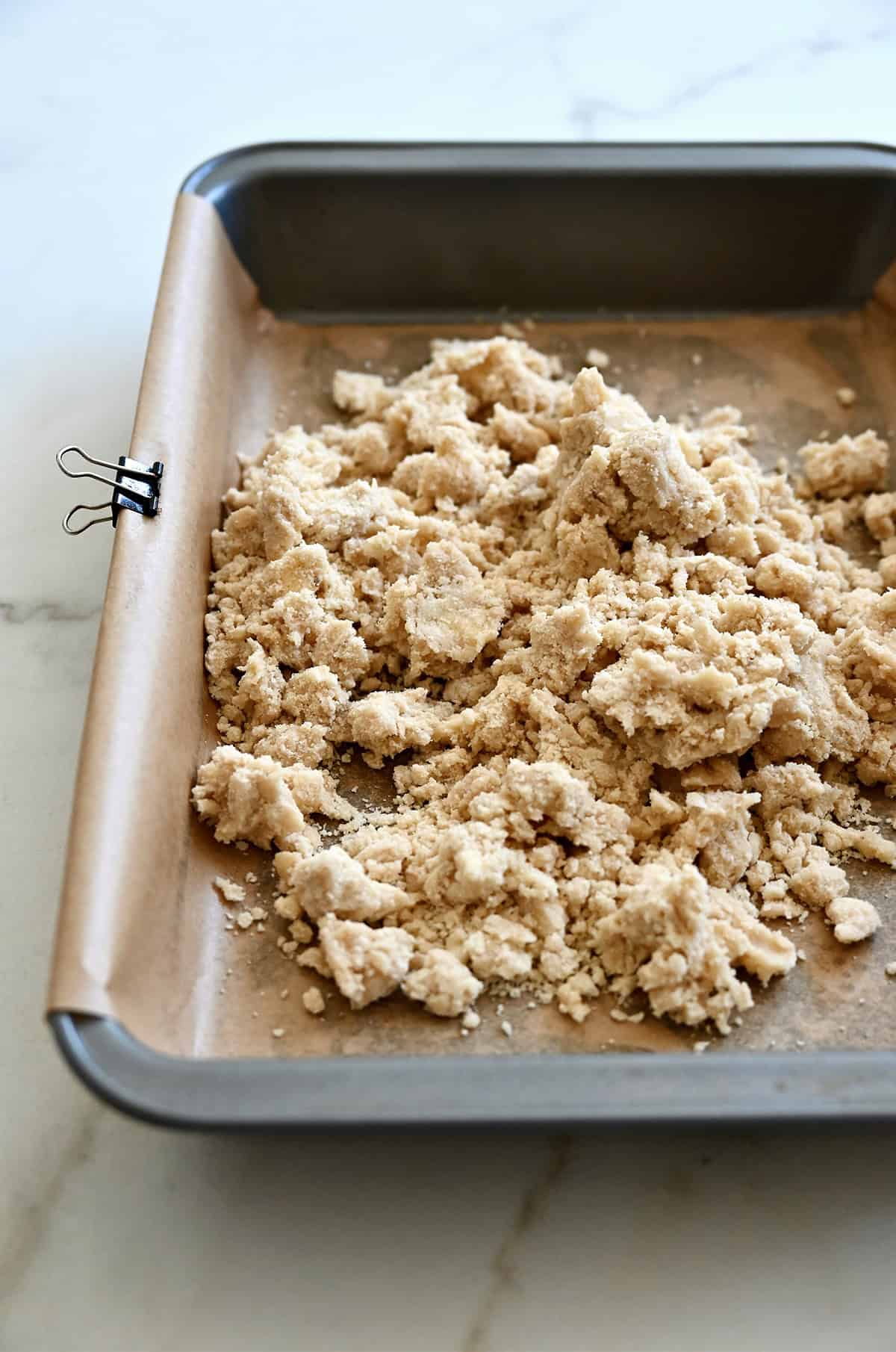Shortbread dough in a 9x13 baking pan lined with parchment paper.