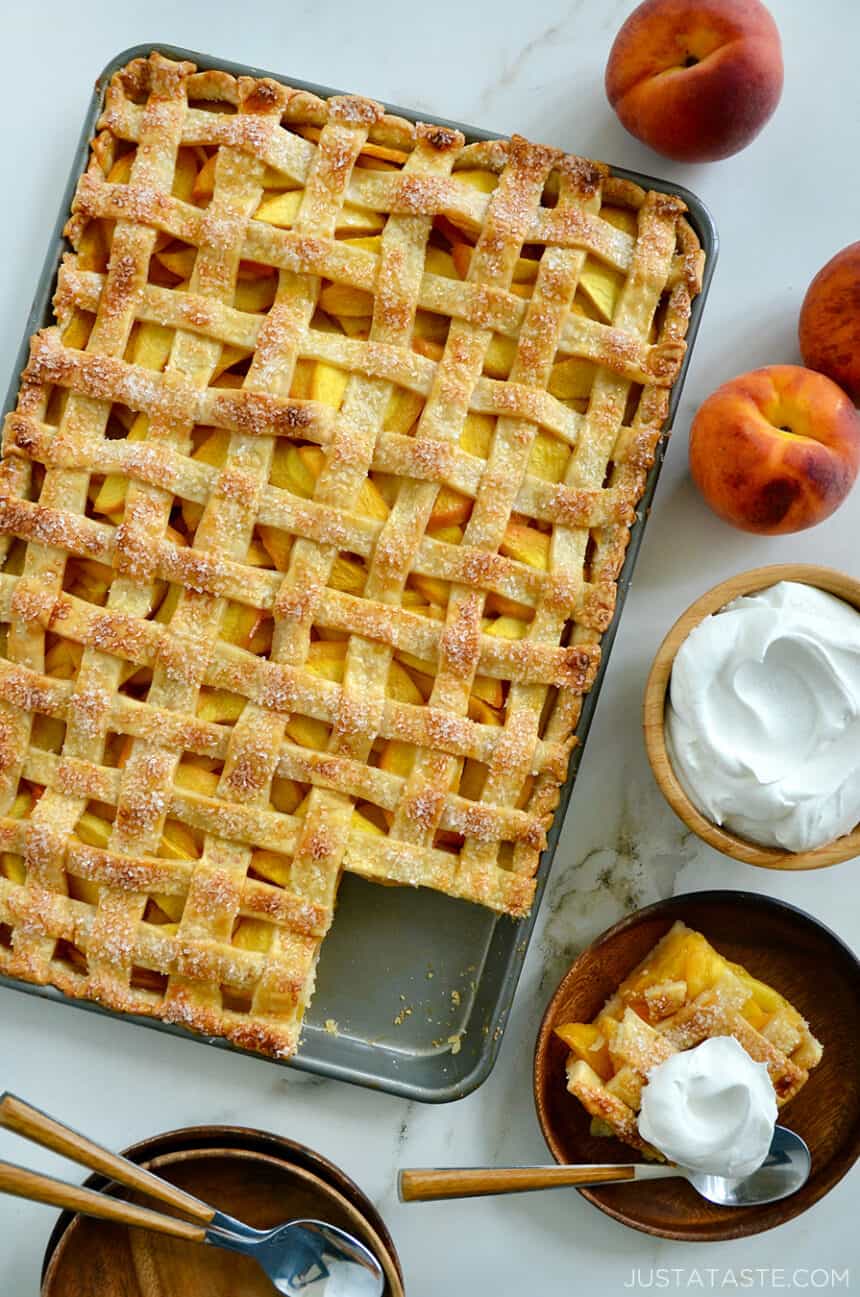 A slab pie surrounded by whipped cream and peaches